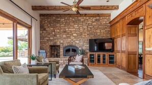 A cozy living room with a stone fireplace, wooden cabinets, and a television.