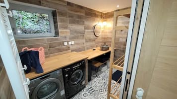 A compact laundry area with a washing machine, dryer, and a wooden counter.