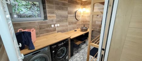 Un espace buanderie compact comprenant un lave-linge, un sèche-linge et un plan de travail en bois.