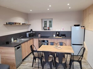 A compact kitchen with a dining table, chairs, a refrigerator, and a microwave.