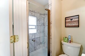 Ein Badezimmer mit Toilette, einer Dusche mit Marmorfliesen und einem gerahmten Bild an der Wand.