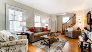 Un salon spacieux comprenant un canapé, des fauteuils, une table basse et un escalier menant à un autre niveau.