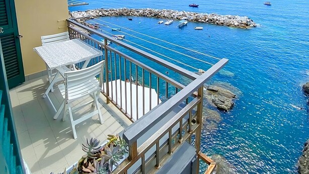 A balcony with a clear view of the sea, a white table and chairs, and a railing. - Apartment La Scogliera - Riomaggiore (Riomaggiore)