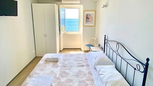 A bedroom with a bed, a wardrobe, a chair, and a view of the sea. - Apartment La Scogliera - Riomaggiore (Riomaggiore)