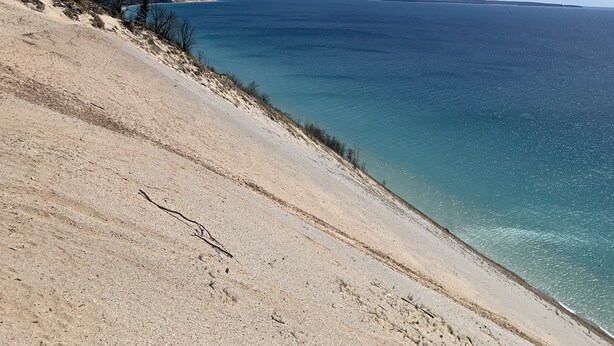 Un paisaje costero con cielo despejado, una playa arenosa y vista al mar.