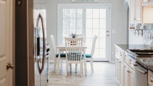 Una cocina con armarios de madera, un ventilador de techo, una mesa de comedor con sillas y un ventanal con vistas.