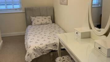 A bedroom with a bed, a bedside table with a mirror, and a chair.