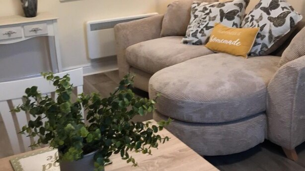 A cozy living room with a beige sofa, a dining table with chairs, a potted plant, and a window with blinds. - 2-bed Duplex Sleeps 3 With Fireplace (Doncaster)