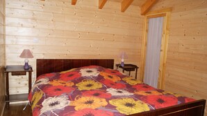 Ein Schlafzimmer in einer Holzhütte mit einem Bett, zwei Nachttischen und einem Fenster.
