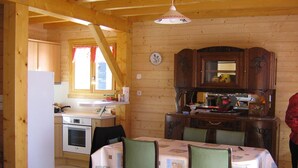 Ein Holzinnenraum mit Küchenbereich, Esstisch, Stühlen und einem Kühlschrank.