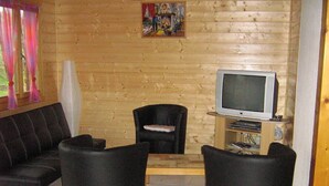 Ein gemütliches Wohnzimmer mit einer Couch, zwei Sesseln, einem Fernseher und einem kleinen Tisch.