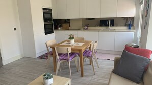 A compact living space with a dining area, kitchenette, and a sofa. - Spacious and bright modern styling 3 bed flat (LONDON)