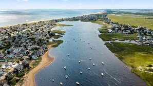 Ein Luftbild einer Küstenstadt mit einem Yachthafen voller Boote, umgeben von Wohngebieten und einem Strand.