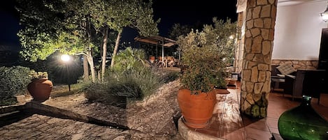 An outdoor patio area with stone flooring, potted plants, and outdoor furniture.