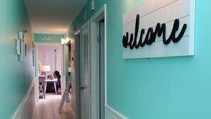 A hallway with a 'welcome' sign, light fixtures, and a tiled floor.