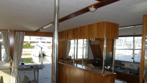 Eine kleine Kombüchenzeile mit Holzausstattung, einer Edelstahlspüle und einem Fenster mit Blick auf den Hafen.