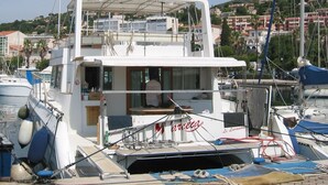 Eine weiße Yacht liegt in einer Marina festgemacht, mit einer Deckfläche, einer Kabine und einem Hubschrauberlandeplatz.
