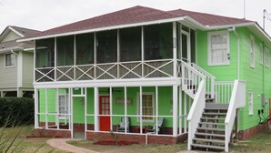 A two-story house with a green exterior and a white porch. - Location Location Location! Classic Beach Cottage less than 1-min walk to beach! (Murrells Inlet)