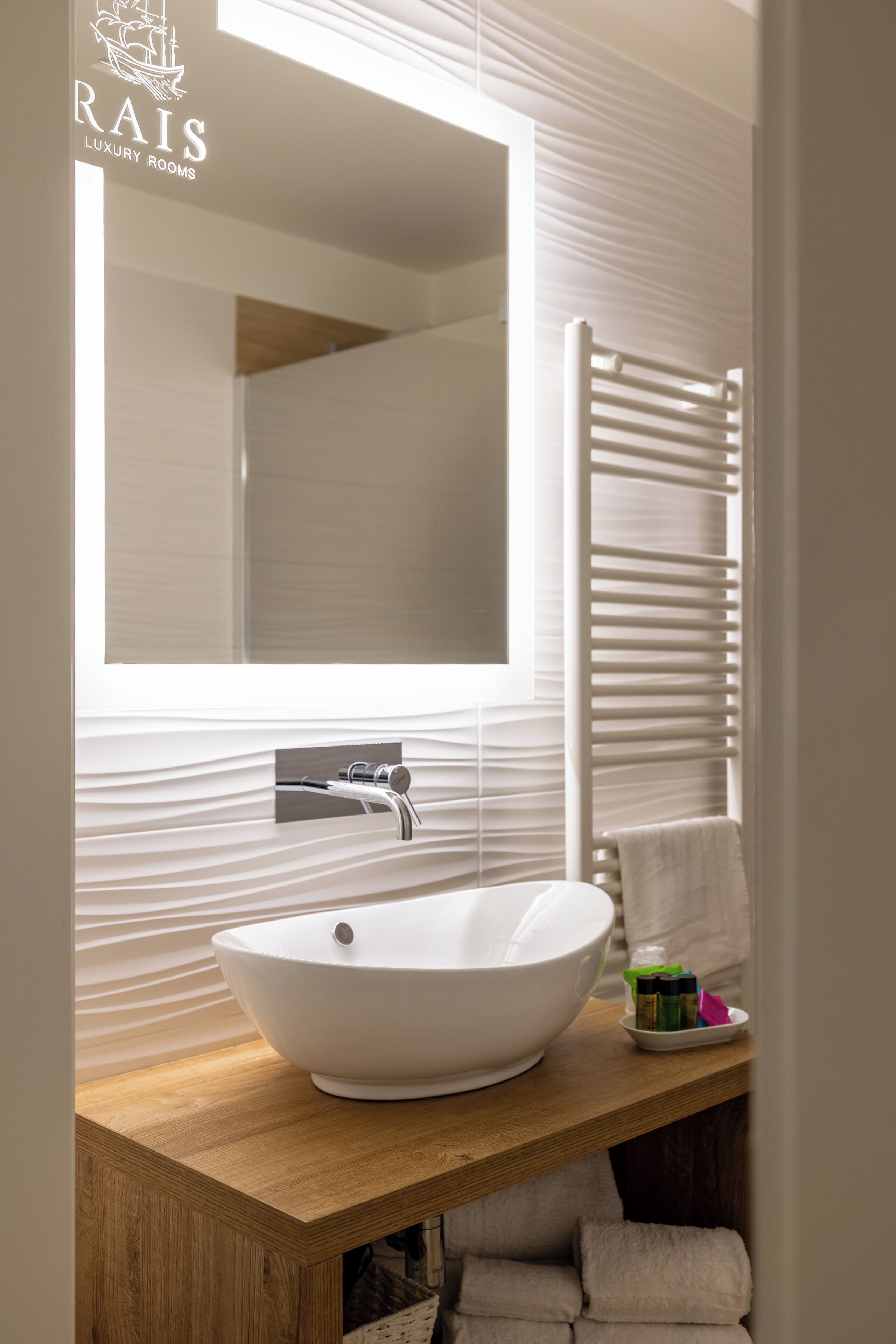 A modern bathroom with a large mirror, a vessel sink, and a towel rack.