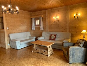 Relax in this inviting cabin-style room with a sofa set, armchair, and wooden coffee table.