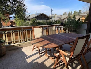 Enjoy al fresco dining on the patio with a wooden table and chairs, surrounded by lush trees and scenic views.