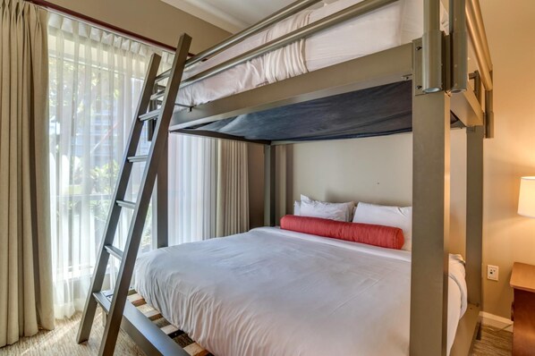 A bunk bed with a ladder, white bedding, and a red pillow.