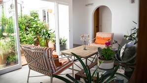 Un espace de vie à aire ouverte comprenant une table en bois, des fauteuils à rayures et une vue sur un jardin grâce à des portes vitrées.