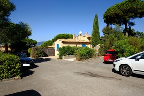 A residential street with parked cars, a house with a blue door, and a large tree. - Apartment with sea view on the Côte d'Azur (Gigaro La Croix Valmer)