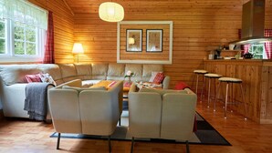 A cozy cabin interior with a sofa, chairs, a dining table, and a bar area. - Accommodation in the forest by the lake. Come and visit us in Sweden (Gunnarskog)