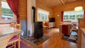 A cozy cabin interior with a wooden interior, a fireplace, a dining table, and a sofa. - Accommodation in the forest by the lake. Come and visit us in Sweden (Gunnarskog)