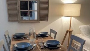 Et spisebord dækket med tallerkener, glas og bestik, omgivet af stole, med en lampe og et spejl på væggen.