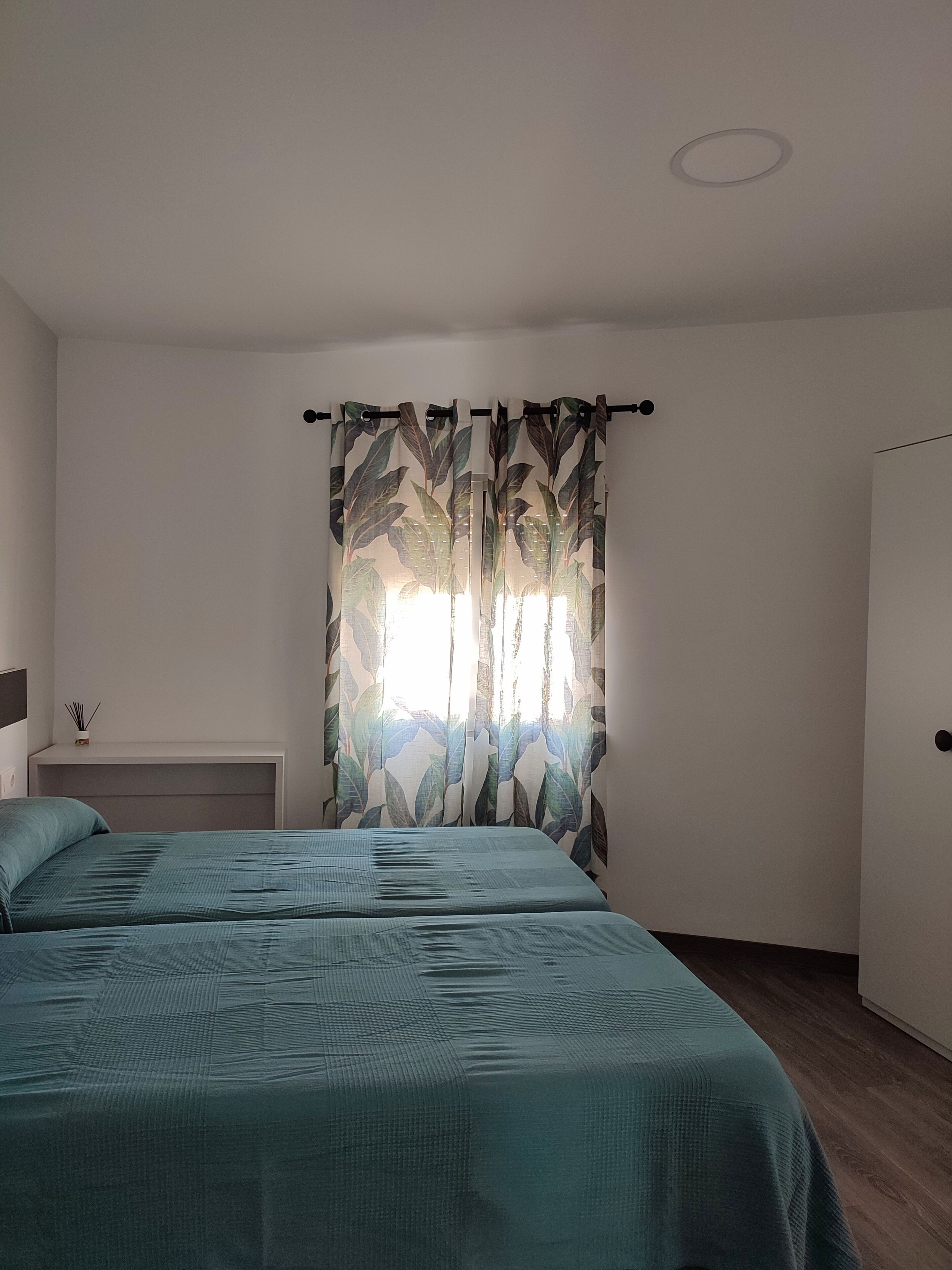 Un dormitorio con dos camas, un armario blanco y una lámpara en el techo.