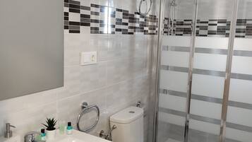 A modern bathroom with a white sink, vanity, toilet, and a glass shower enclosure.