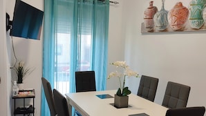 A modern dining area with a white table, black chairs, and a potted orchid. - Cozy, bright, terrace-solarium, rustic living room. Very close to Madrid... (Villarejo de Salvanés)