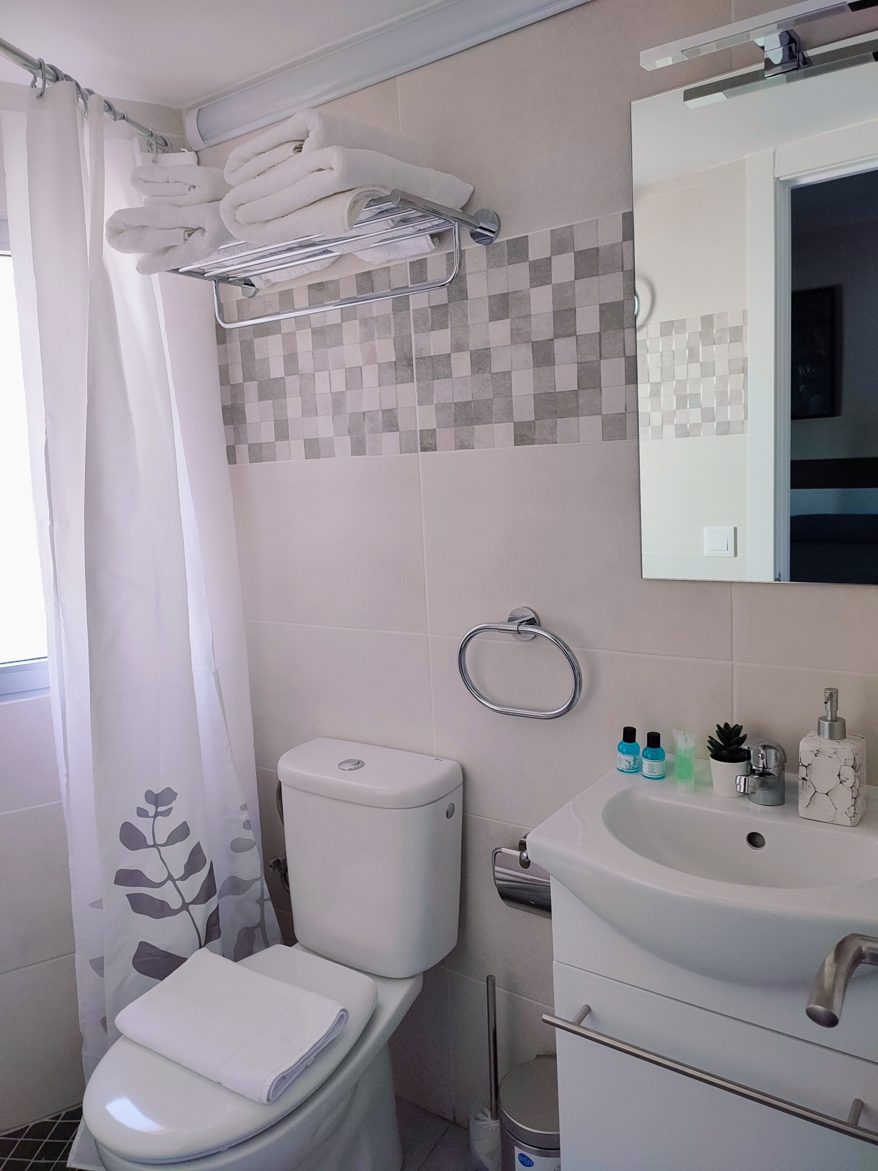 Un baño con inodoro, lavamanos y perchero para toallas.