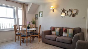 A living room with a sofa, chairs, a dining table, and a wall-mounted light fixture. - HEART OF INVERNESS MODERN APARTMENT (Inverness)