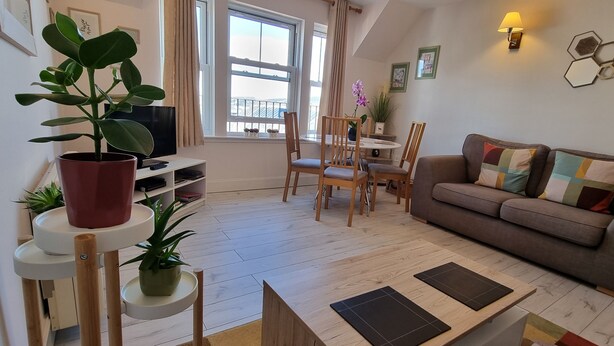 A cozy living room with a sofa, chairs, a TV, and potted plants. - HEART OF INVERNESS MODERN APARTMENT (Inverness)