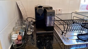 A coffee machine, a glass rack, and a metal rack with a tray on a kitchen counter.