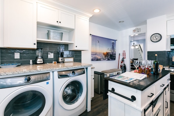 A modern kitchen with built-in appliances, a washing machine, and a dining area with a view of the city.