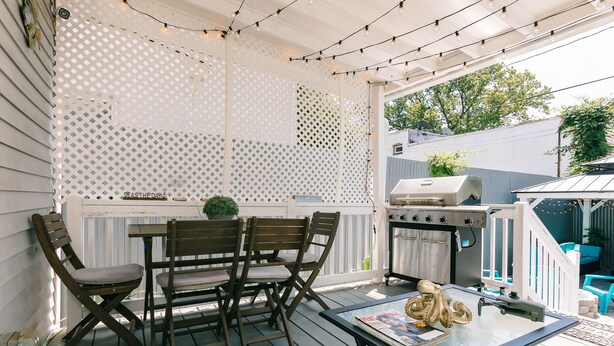 A covered outdoor patio with a table, chairs, a grill, and string lights. - 3-BR house walk to beach, shopping, bars, NYC train. 6-beach passes & 4-bikes. (Asbury Park)