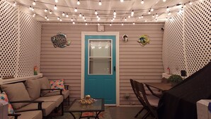 A cozy room with a teal door, string lights, a sofa, a coffee table, and decorative fish wall art. - 3-BR house walk to beach, shopping, bars, NYC train. 6-beach passes & 4-bikes. (Asbury Park)