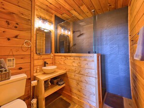 A wooden cabin bathroom with a sink, mirror, and shower. - Best View in Heber Springs | Mountain Cabin for 12 (Heber Springs)