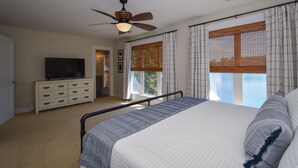 A bedroom with a bed, a TV on a dresser, and large windows with blinds. - Premier Waterfront Location! Big, clear water views! Fire table! (Dadeville)