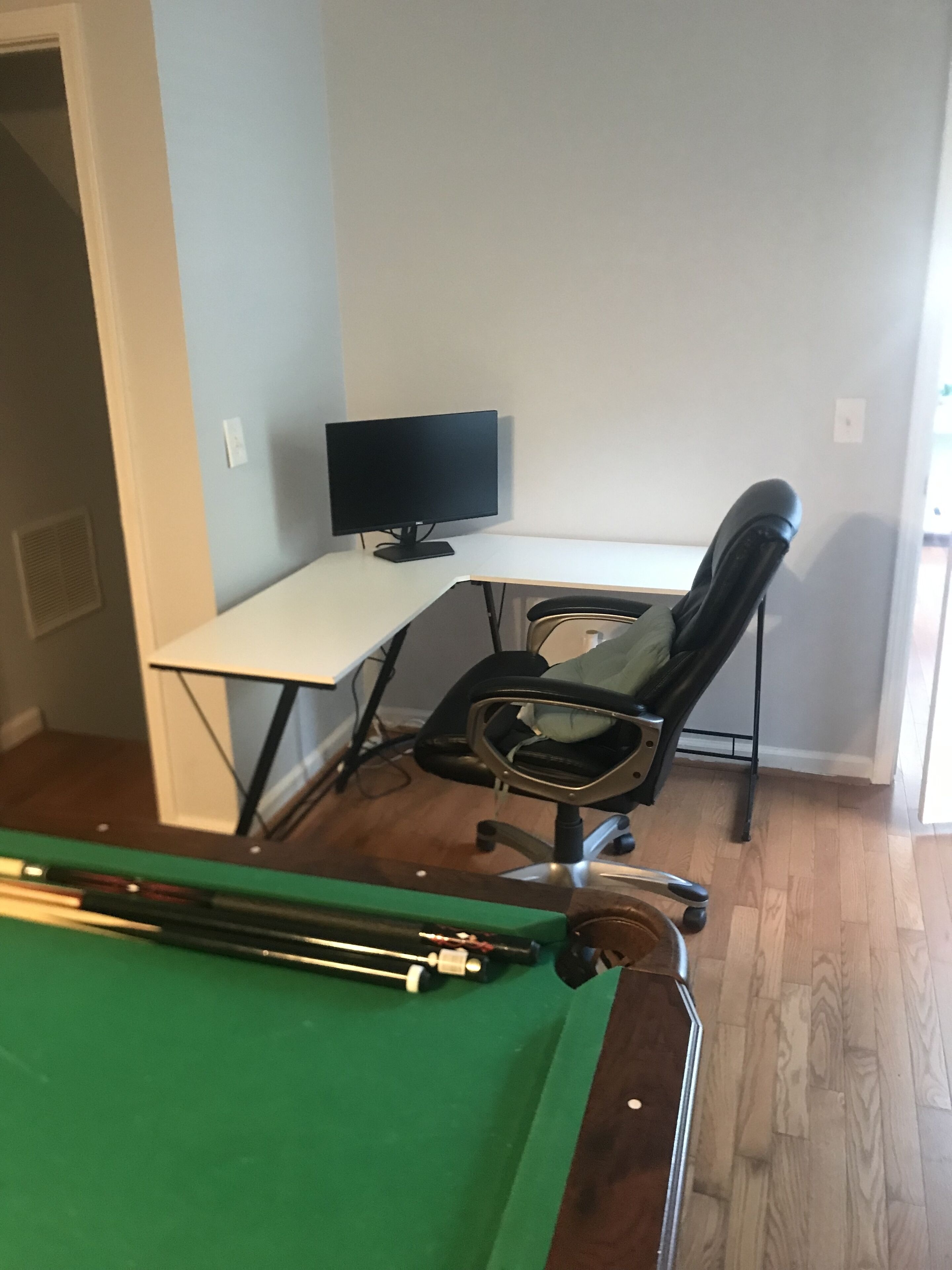 Una habitación con mesa de billar, escritorio con silla y ventana.
