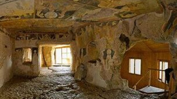 Un intérieur caractérisé par un plafond haut, des portes en arc de cercle et un espace central ouvert.