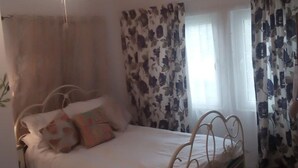 Une chambre à coucher avec un lit, un ventilateur de plafond et des rideaux.