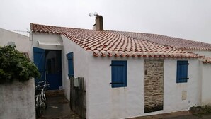 A small, white building with a tiled roof and blue shutters.