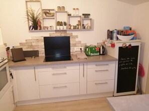 A kitchen with white cabinets, a black stove, and a chalkboard with writing.