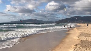 Una spiaggia con persone che passeggiano e fanno volare aquiloni.