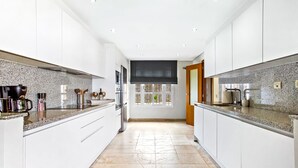 Una cucina moderna con piani di lavoro in granito, elettrodomestici in acciaio inossidabile e un'ampia finestra che fa entrare molta luce naturale.